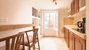 Une cuisine avec des meubles de rangement en bois, un plan de travail et une fenêtre avec des volets.