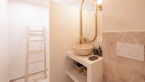 Ein modernes Badezimmer mit einer freistehenden Badewanne, einer Holzleiter und einem weißen Waschtisch mit einer großen Spüle.