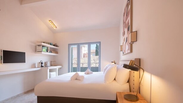 Une chambre à coucher avec un lit, une table de chevet, une lampe, une télévision et une fenêtre donnant sur un beau paysage.