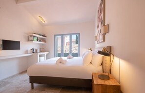 A bedroom with a bed, bedside table, lamp, TV, and a window with a view. - Wonderful Studio in the Heart of St Tropez (Saint-Tropez)