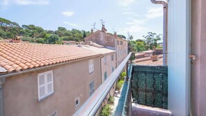 Un quartier résidentiel caractérisé par des toits recouverts de tuiles en terre cuite, une ruelle étroite et un bâtiment doté d’une structure en treillis vert.