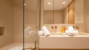 Une salle de bain moderne avec un grand miroir, deux vasques et une douche séparée par une paroi en verre.
