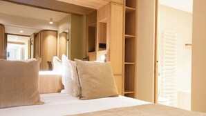Une chambre avec un grand lit, une tête de lit en bois et des étagères intégrées.