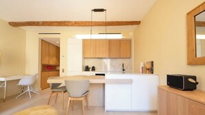 Une cuisine moderne avec des meubles en bois, un îlot central et un coin repas comprenant une table et des chaises blanches.