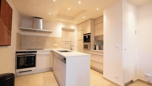 Een moderne keuken met ingebouwde apparatuur, een centraal eiland en inbouwspots.