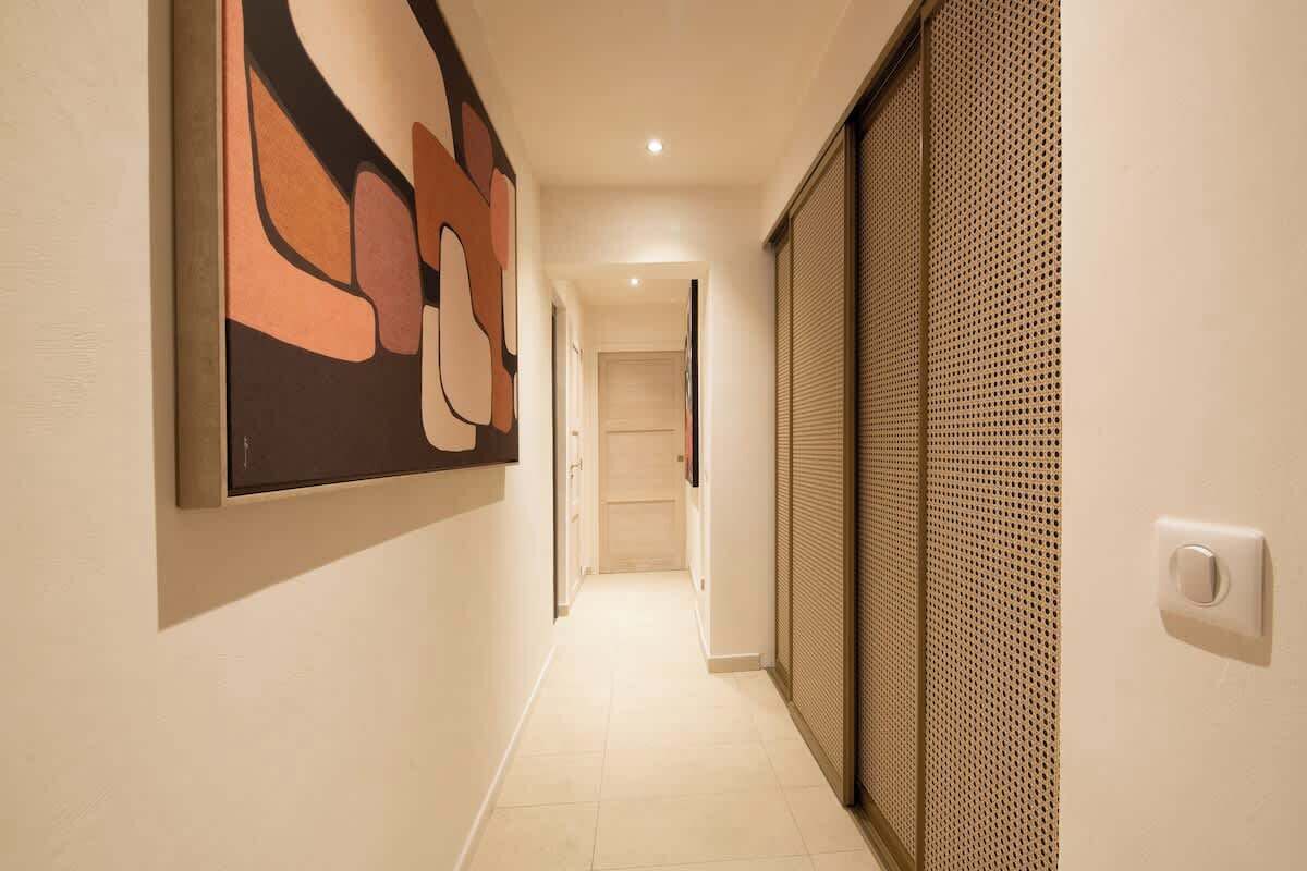 Een hal met een modern design, met een groot abstract schilderij links en een structuurwand rechts.