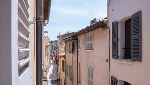 Une rue étroite, bordée de bâtiments des deux côtés, qui se caractérise par une architecture traditionnelle et la présence de volets.