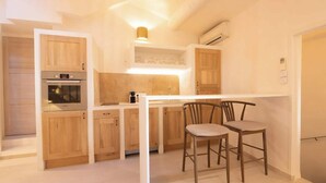 Une cuisine compacte avec des meubles en bois, un four encastré et un coin repas équipé de deux chaises.