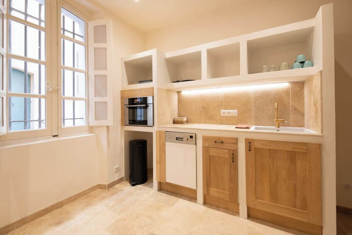 A compact kitchen with built-in appliances, wooden cabinets, and a window.