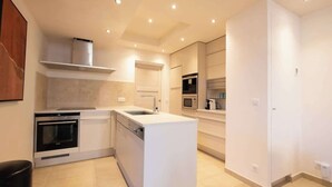 Une cuisine moderne dotée d’appareils électroménagers intégrés, d’un îlot central et d’un éclairage encastré au plafond.