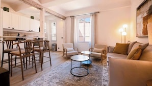 Een moderne woonkamer met een bank, twee fauteuils, een salontafel en een eethoek met stoelen en een tafel.