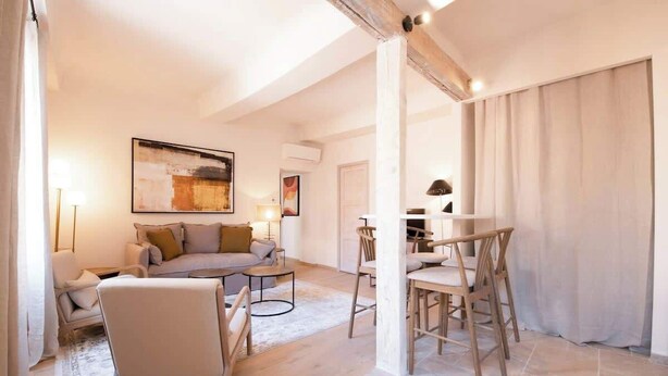 Een moderne woonkamer met een bank, stoelen, een salontafel en een eethoek met stoelen en een tafel.