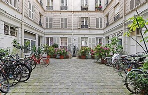 En innergård med ett kullerstenbelagt golv, krukväxter och cyklar som står uppradade längs sidorna.