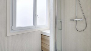 A bathroom with a shower, a window, and a tiled wall. - A Pleasant Studio in La Madeleine-Opéra (Paris)