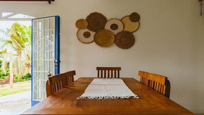 A wooden dining table with a woven placemat, surrounded by wooden chairs. - Country house with heated pool near São Paulo. (Mairiporã)