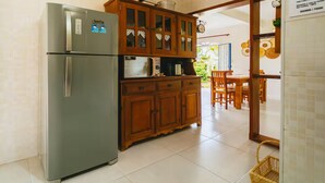 A kitchen with a refrigerator, wooden cabinets, a microwave, and a dining area with a table and chairs. - Country house with heated pool near São Paulo. (Mairiporã)