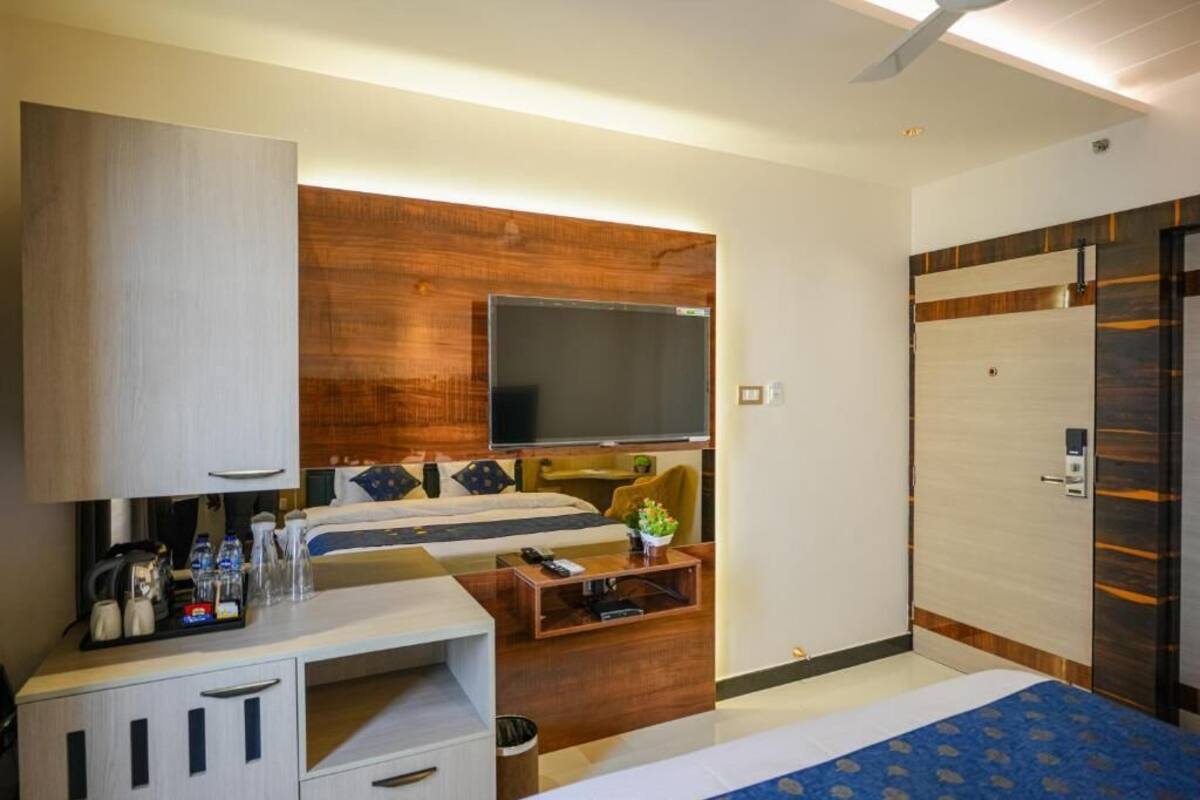 Una habitación de hotel con una cama, un escritorio con computadora, un televisor y un armario.
