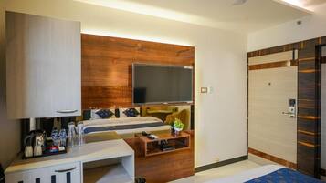 A hotel room with a bed, a desk with a computer, a television, and a wardrobe.