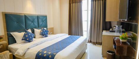 A modern hotel room with a large bed, a desk, and a TV.