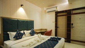 A hotel room with a large bed, a headboard, a bedside table, a chair, and a wardrobe. - Sri Shyam Villas (VARANASI)