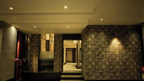 A modern hallway with patterned stone walls, a metal elevator, and a staircase leading to another area. - Sri Shyam Villas (VARANASI)