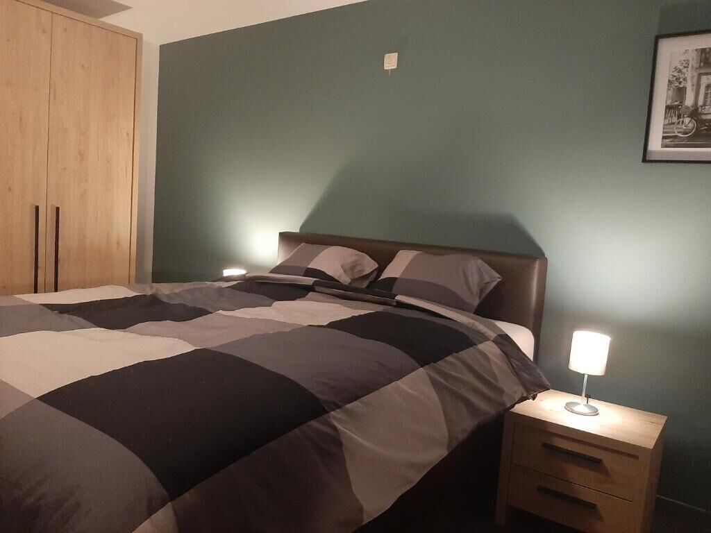 Un dormitorio con una cama, mesitas de noche, un armario de madera y un cuadro enmarcado en la pared.