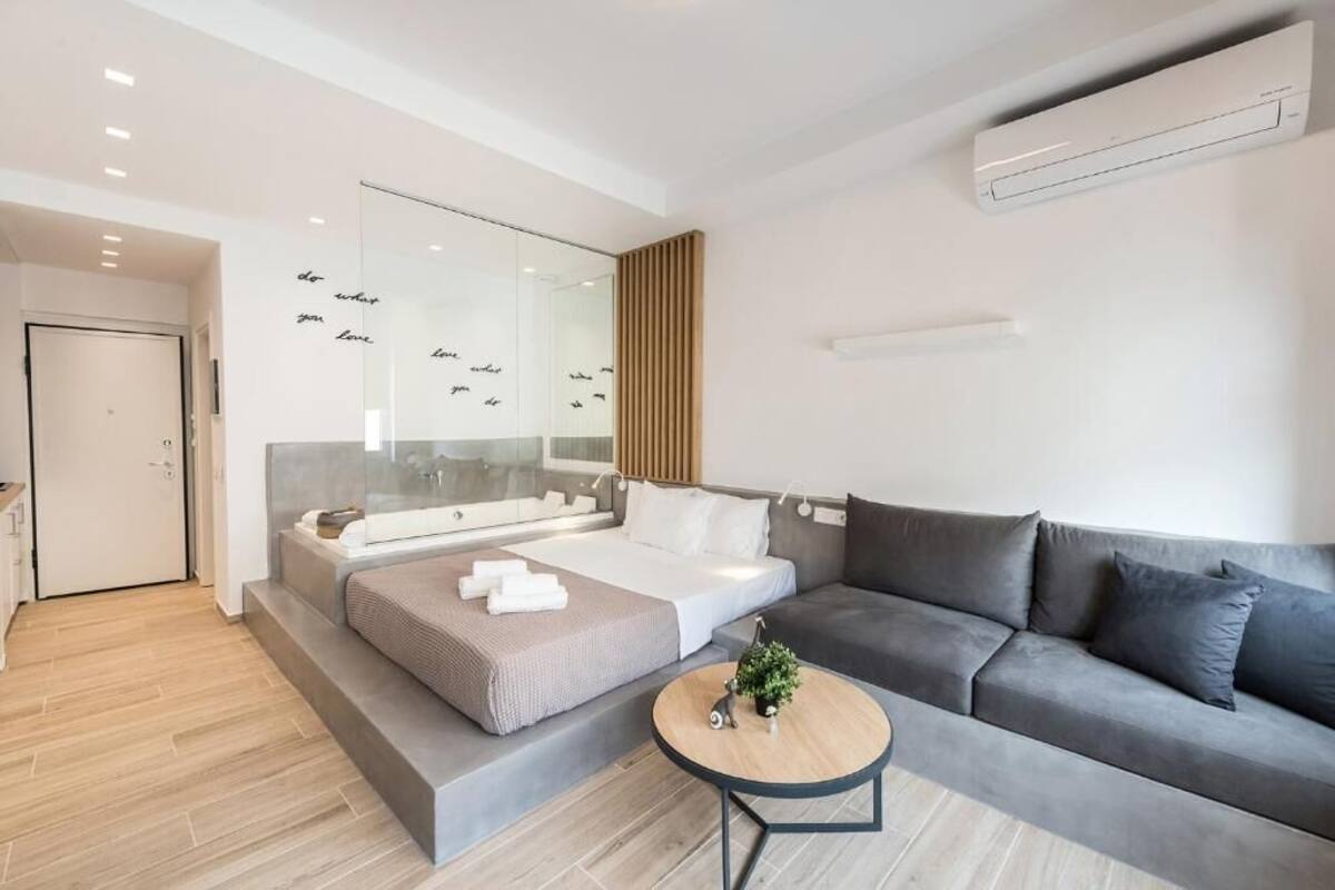 Un salon moderne avec un canapé, une table basse et un lit adossé à un mur en verre.