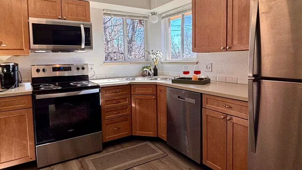 Une cuisine moderne avec des meubles en bois, des appareils en acier inoxydable et une fenêtre donnant sur les arbres.