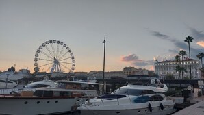 A marina with yachts docked, a Ferris wheel in the background, and a building with 'SPLENI' signage. - Family apartment with swimming pool and sea view, quietly located with parking. (Cannes)
