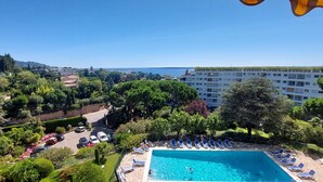 A pool area with lounge chairs and a view of the sea. - Family apartment with swimming pool and sea view, quietly located with parking. (Cannes)