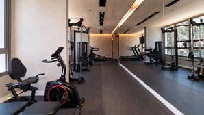 Uma academia com equipamentos de ginástica, amplas janelas e um painel de espelhos.