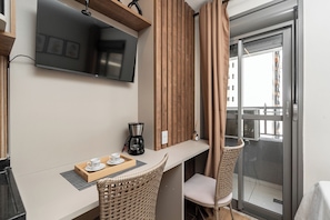 Une chambre d’hôtel moderne équipée d’un téléviseur à écran plat, d’une machine à café et de fauteuils en osier.