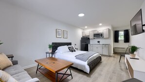 Un appartamento moderno e funzionale con un letto singolo, un piccolo angolo pranzo e angolo cottura.