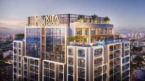 Ein hoch aufragendes Gebäude mit modernem Design, das ein markantes Logo oben trägt und mehrere mit Grünpflanzen bepflanzte Balkone aufweist.