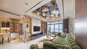 Ein modernes Wohnzimmer mit einem grünen Sofa, einem Couchtisch und einem Fernseher. Es gibt eine Küchenzeile mit einer Arbeitsfläche und Schränken.