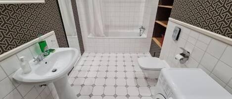A compact bathroom with a sink, toilet, and washing machine.
