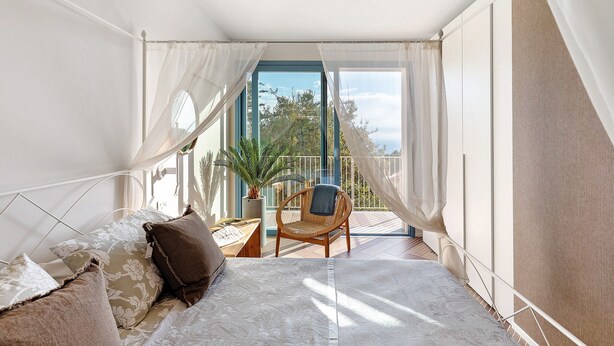 Un balcón con una cama, una silla y una planta en maceta.
