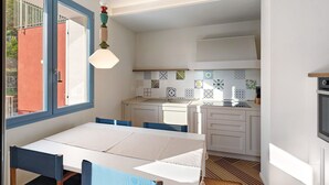 Una cocina compacta con armarios blancos, salpicadero de azulejos y un comedor con mesa y sillas.