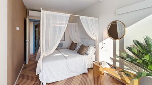 Un dormitorio con cama con dosel, mesita de noche, espejo y una planta en maceta.