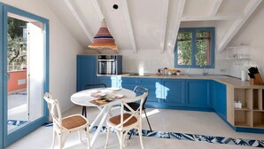 A kitchen with blue cabinets, a white ceiling, and a dining area with a table and chairs. - Apartment 'Verde Mare' with Sea View, Private Terrace and Wi-Fi (Andora)