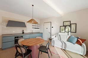 A modern living space with a kitchen, dining area, and a white sofa with cushions. - Apartment 'Corallo' with Sea View, Private Terrace and Wi-Fi (Andora)