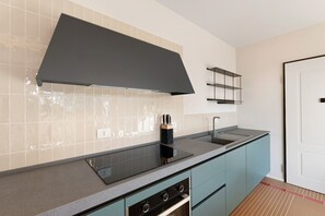 A modern kitchen with a black range hood, a built-in stove, a sink, and light blue cabinets. - Apartment 'Corallo' with Sea View, Private Terrace and Wi-Fi (Andora)