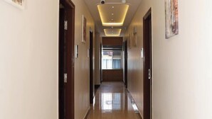 A hotel hallway with a modern design, featuring a long corridor with doors on either side, recessed lighting, and artwork on the walls. - Hotel Thanga Airaa (Bengaluru)