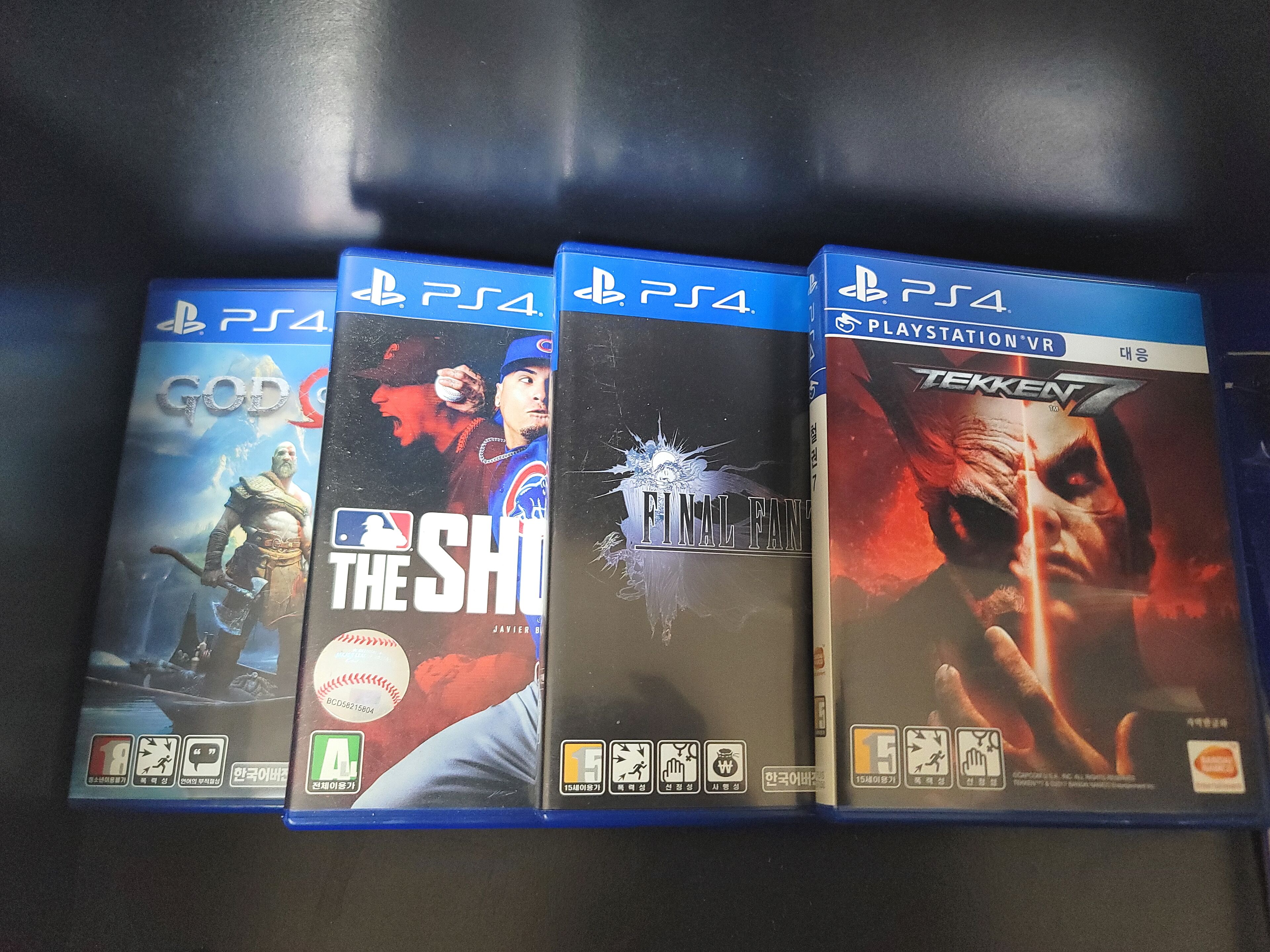 Four PlayStation 4 game cases on a shelf.
