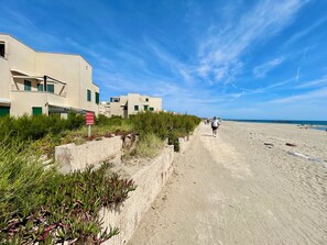 En kystpromenade med bygninger, klar himmel og en strand.