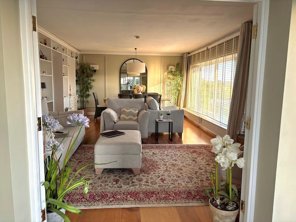 A living room with a sofa, ottoman, and a dining area with chairs and a table.
