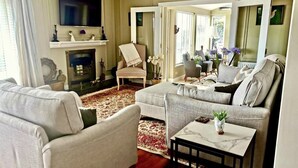 Un salon avec une cheminée, un téléviseur et un coin salon comprenant une table basse.