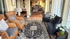 Un salon avec des fauteuils en osier, un tapis à motifs et un canapé.