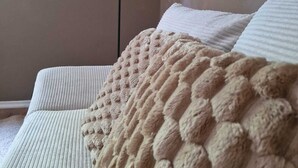 Ein Schlafzimmer mit einem Bett, einer weißen Decke und einer schwarzen Stehlampe.