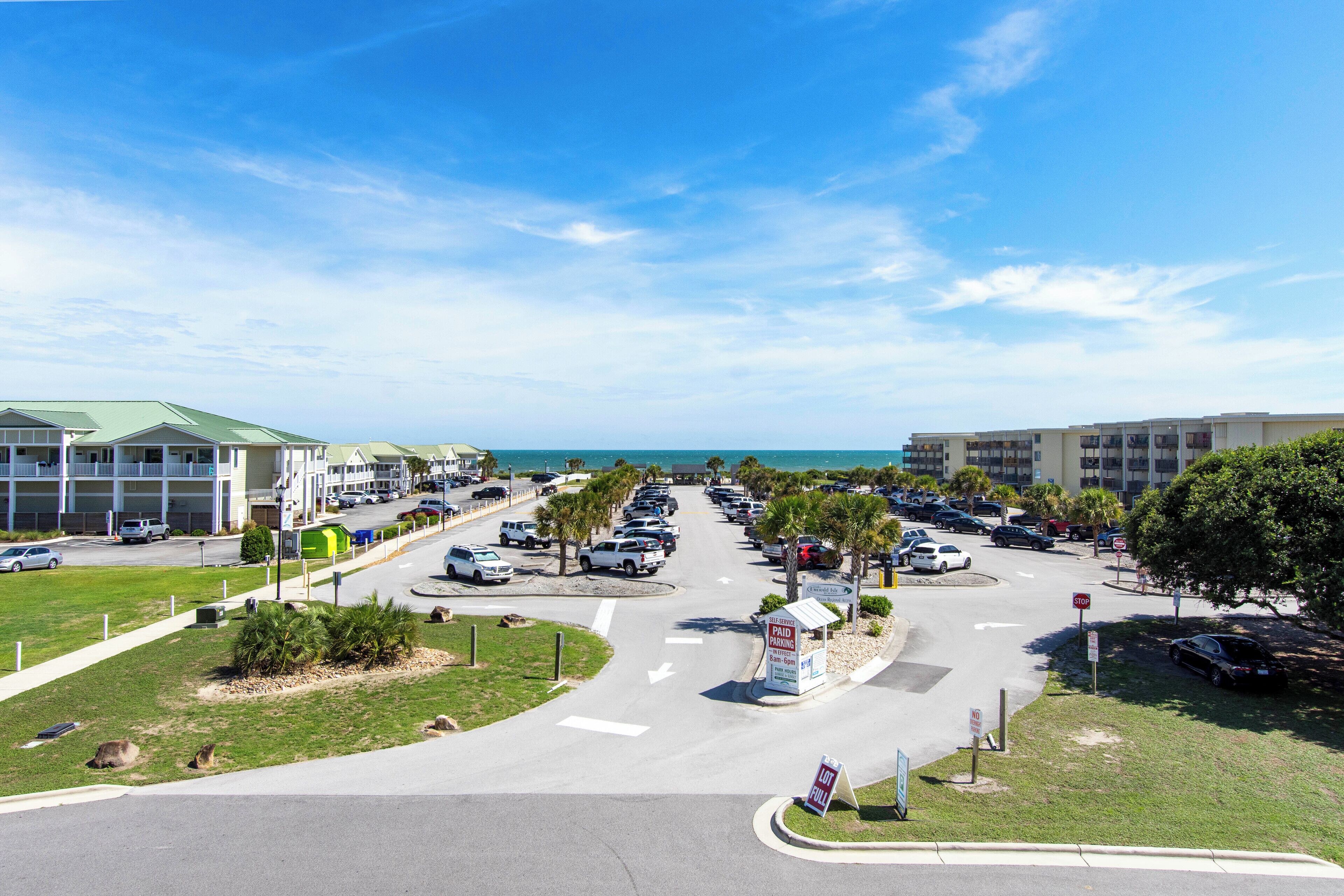 A parking lot with multiple cars, a stop sign, and a building with a green roof.